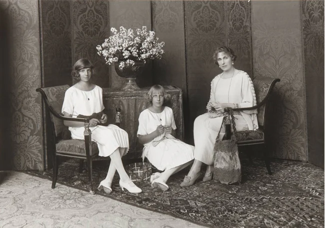 La reina Victoria Eugenia haciendo ganchillo con las infantas Beatriz y María Cristina, para el ropero de Caridad de Santa Victoria, h.1920.